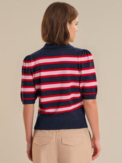 Woman wearing a red, white, and blue striped sweater on a beige background