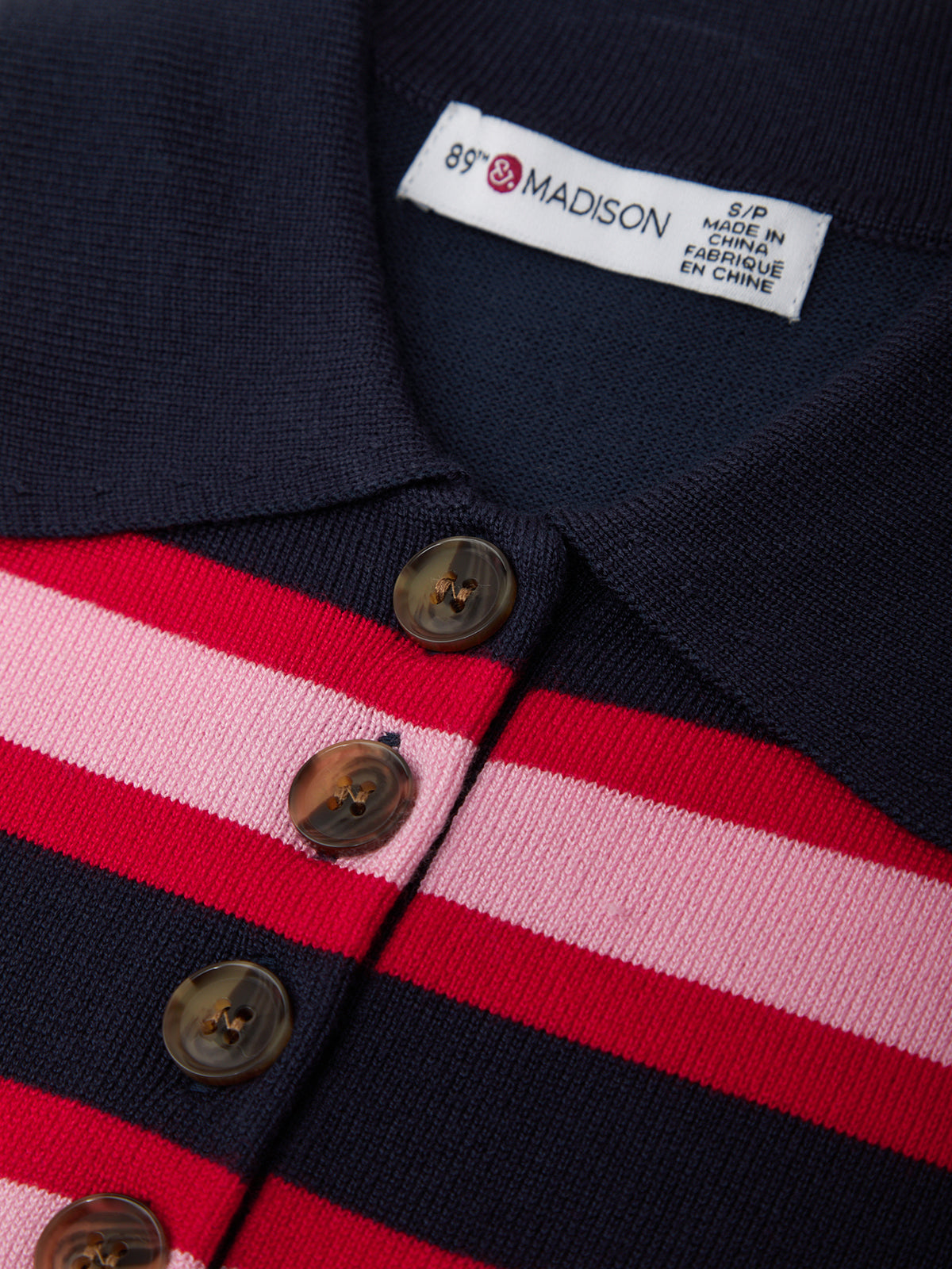 Close-up of a navy, red, and pink striped garment with a brand label.