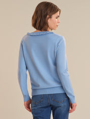 Woman wearing a light blue sweater with a textured collar against a beige background