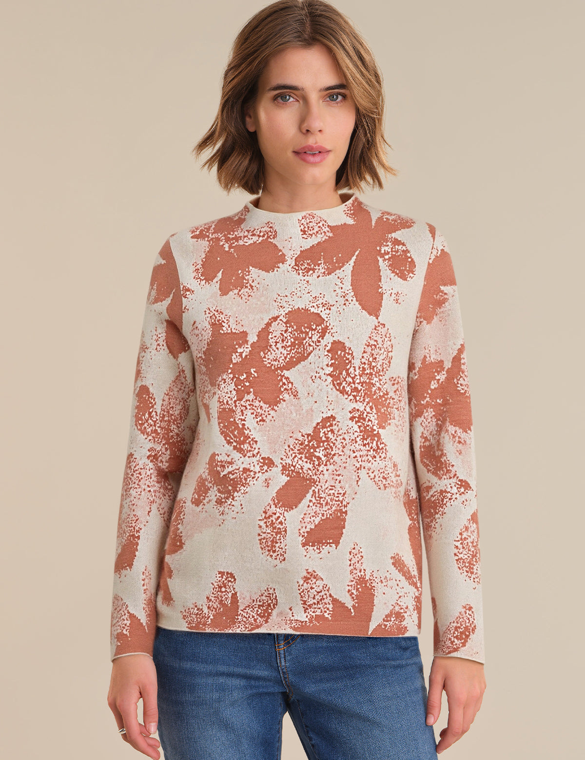 Woman wearing a patterned long-sleeve top against a beige background