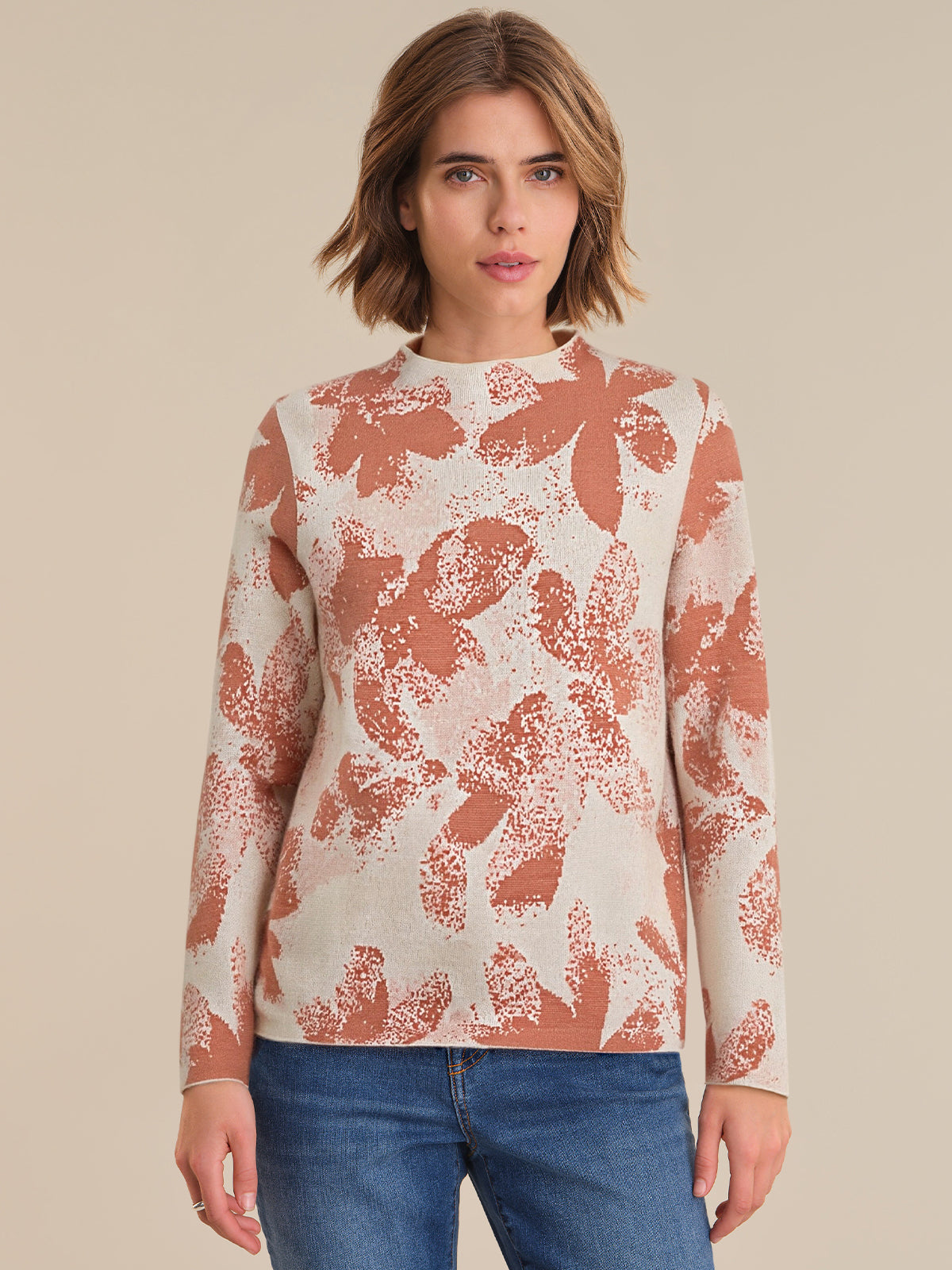 Woman wearing a patterned long-sleeve top against a beige background
