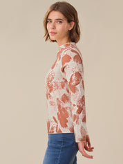 Woman wearing a floral lace top with long sleeves on a beige background