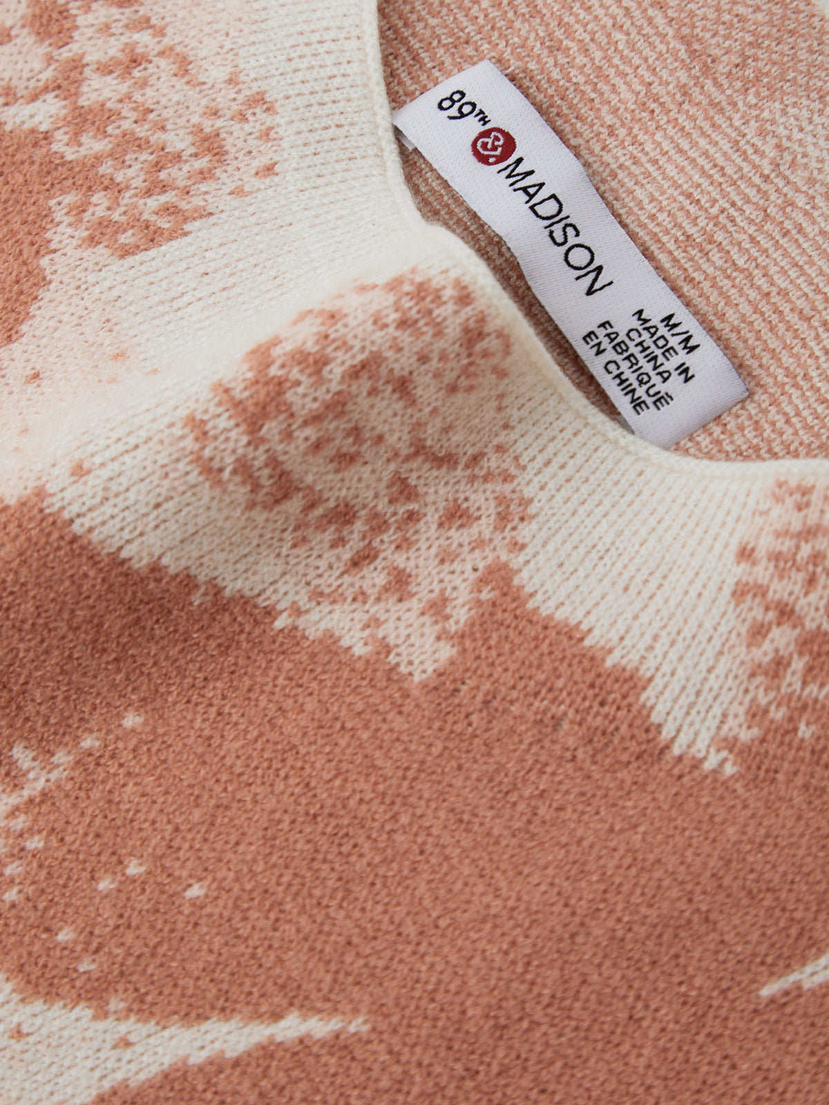 Close-up of a textured fabric with a Madison label on a pink and white patterned background