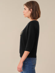 Woman wearing a black sweater with a logo on a beige background