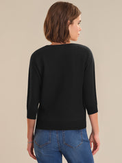Woman wearing a black sweater and blue jeans on a beige background