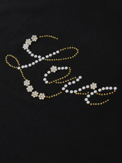Decorative word with pearls and gold accents on a black background