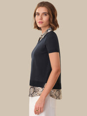 Woman wearing a black top with snake print trim on a beige background