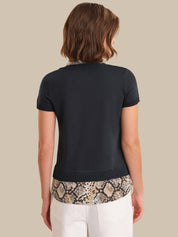 Person wearing a black top with snake print trim on a beige background