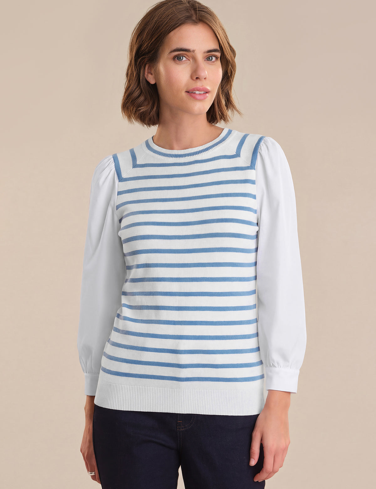 Woman wearing a blue and white striped sweater over a white shirt on a beige background