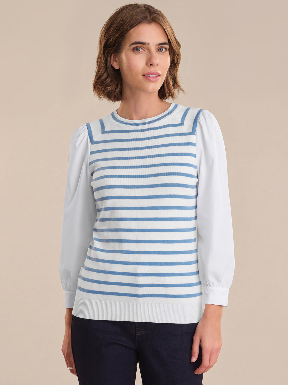 Woman wearing a blue and white striped sweater over a white shirt on a beige background