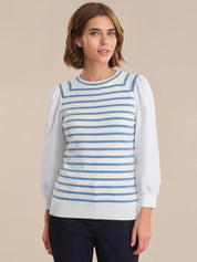 Woman wearing a blue and white striped sweater over a white shirt on a beige background