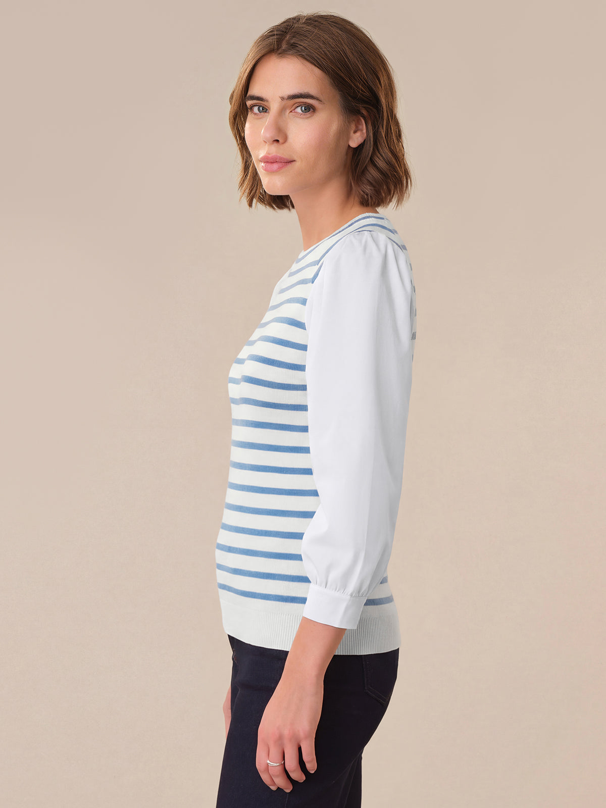 Woman wearing a light blue and white striped sweater on a beige background