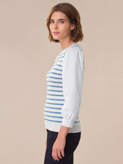 Woman wearing a light blue and white striped sweater on a beige background