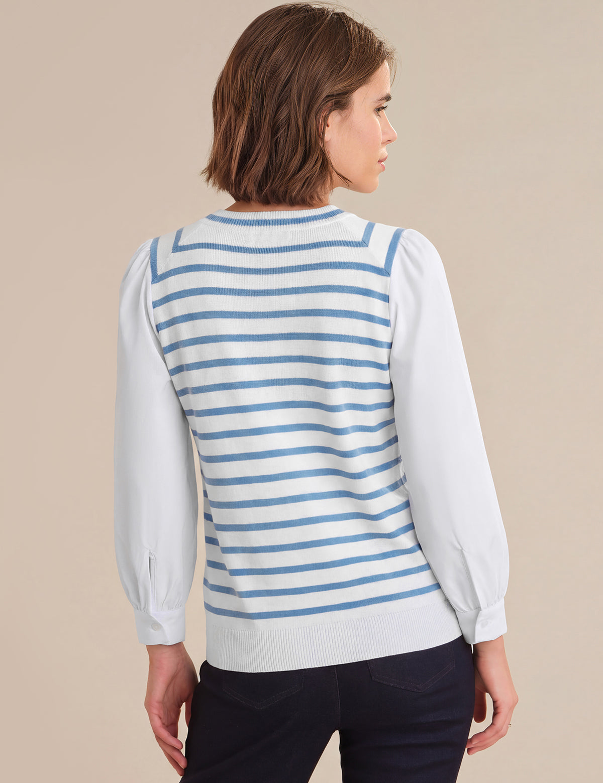 Woman wearing a blue and white striped sweater over a white shirt on a beige background