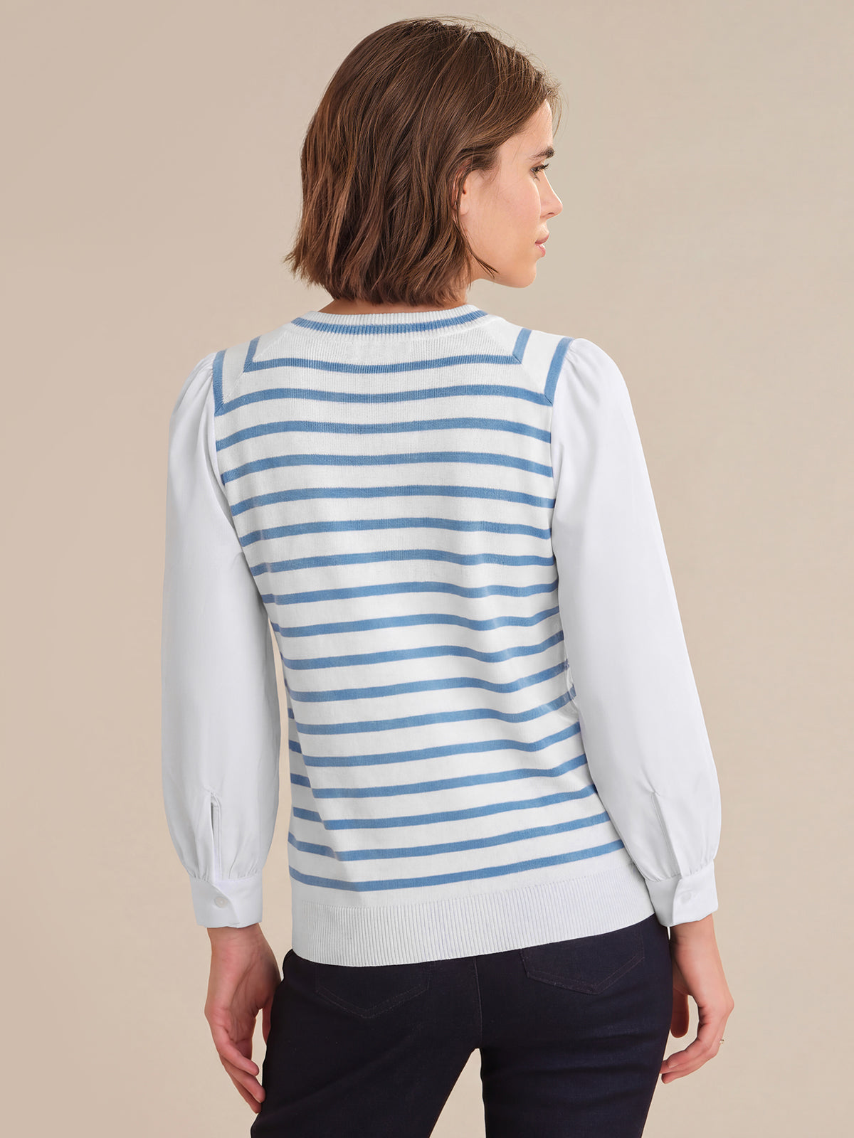 Woman wearing a blue and white striped sweater over a white shirt on a beige background