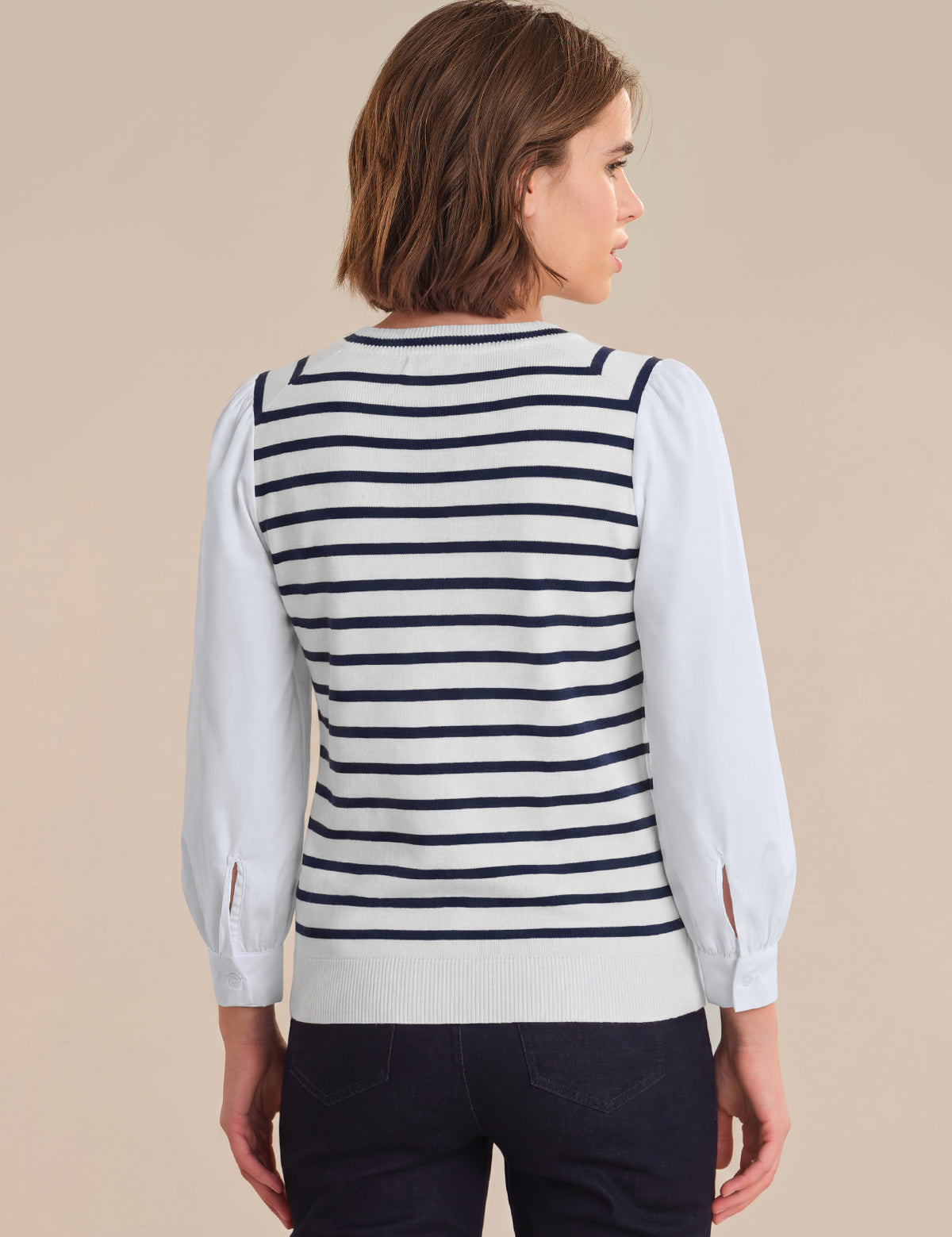 Woman wearing a striped sweater over a white shirt on a beige background