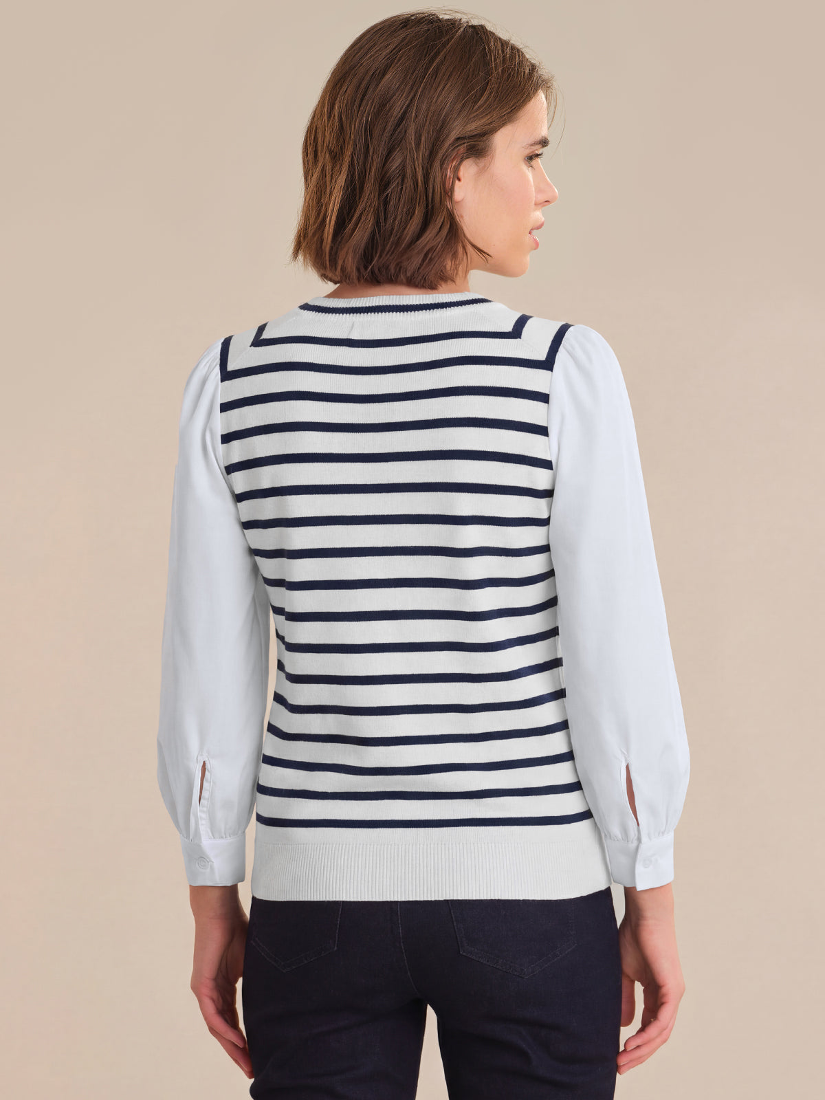 Woman wearing a striped sweater over a white shirt on a beige background