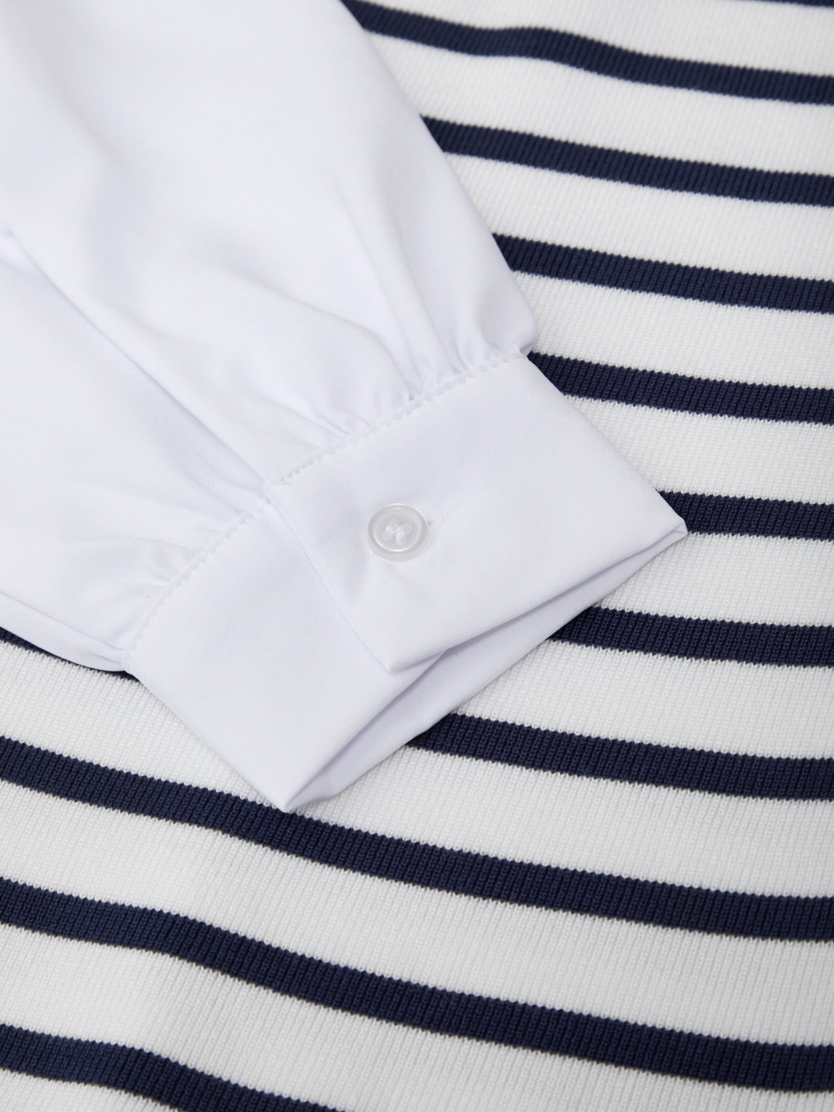 Close-up of a white shirt collar on a navy and white striped fabric background
