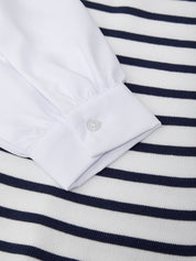Close-up of a white shirt collar on a navy and white striped fabric background