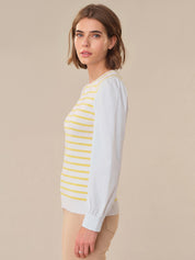 Woman wearing a white long-sleeve shirt with yellow stripes against a beige background