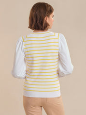 Woman wearing a white long-sleeve shirt with a yellow striped vest on a beige background