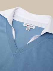 Close-up of a blue sweater with a white shirt underneath and '8th Madison' label.