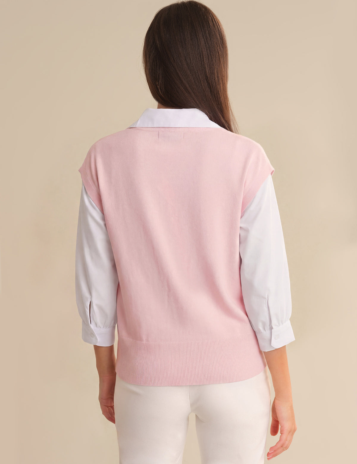 Person wearing a pink vest over a white shirt on a beige background