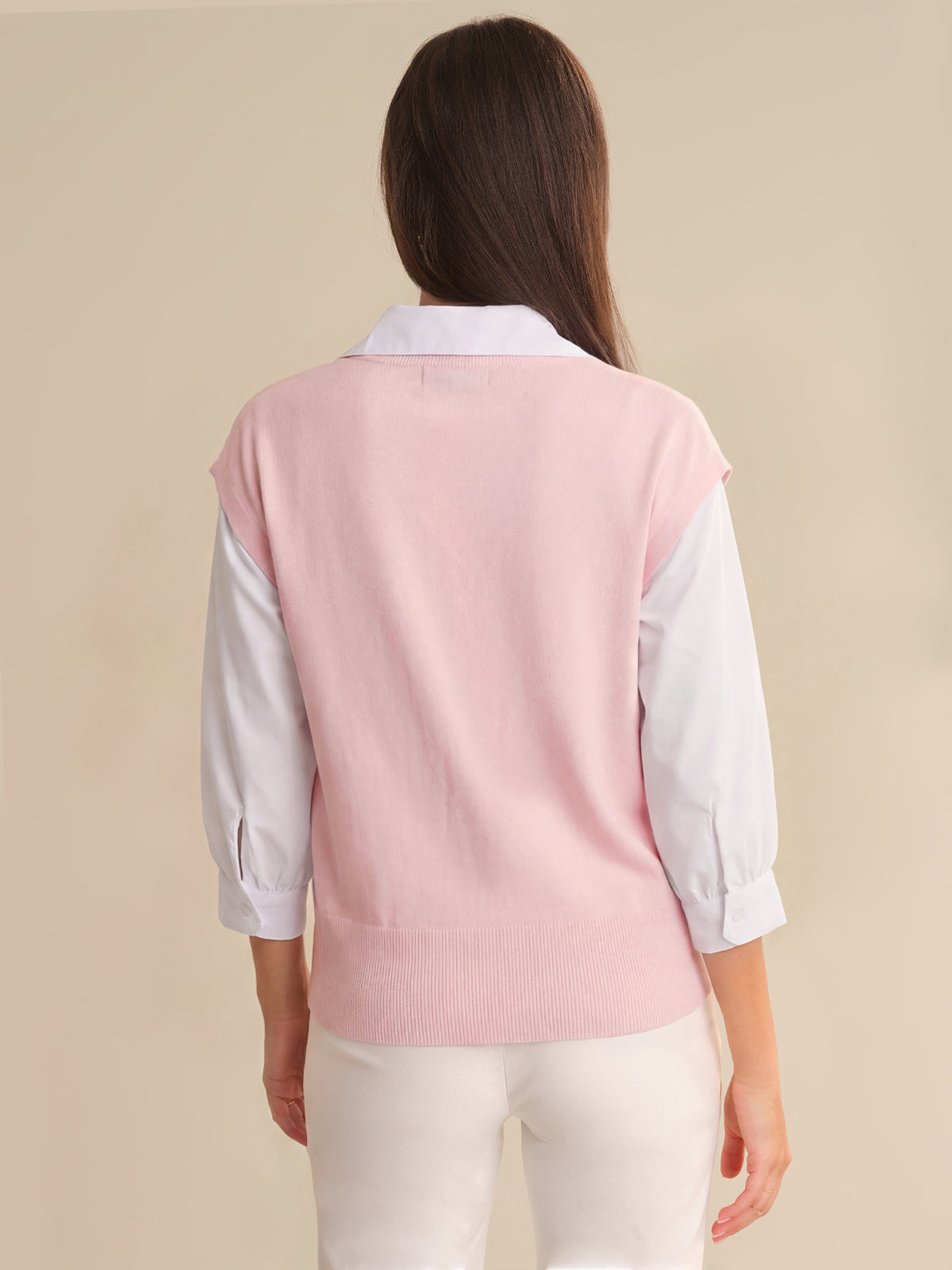 Person wearing a pink vest over a white shirt on a beige background