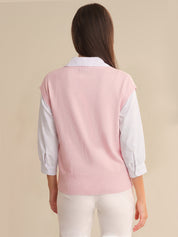 Person wearing a pink vest over a white shirt on a beige background