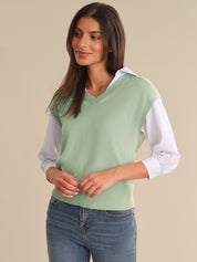 Woman wearing a light green sweater with white sleeves against a beige background