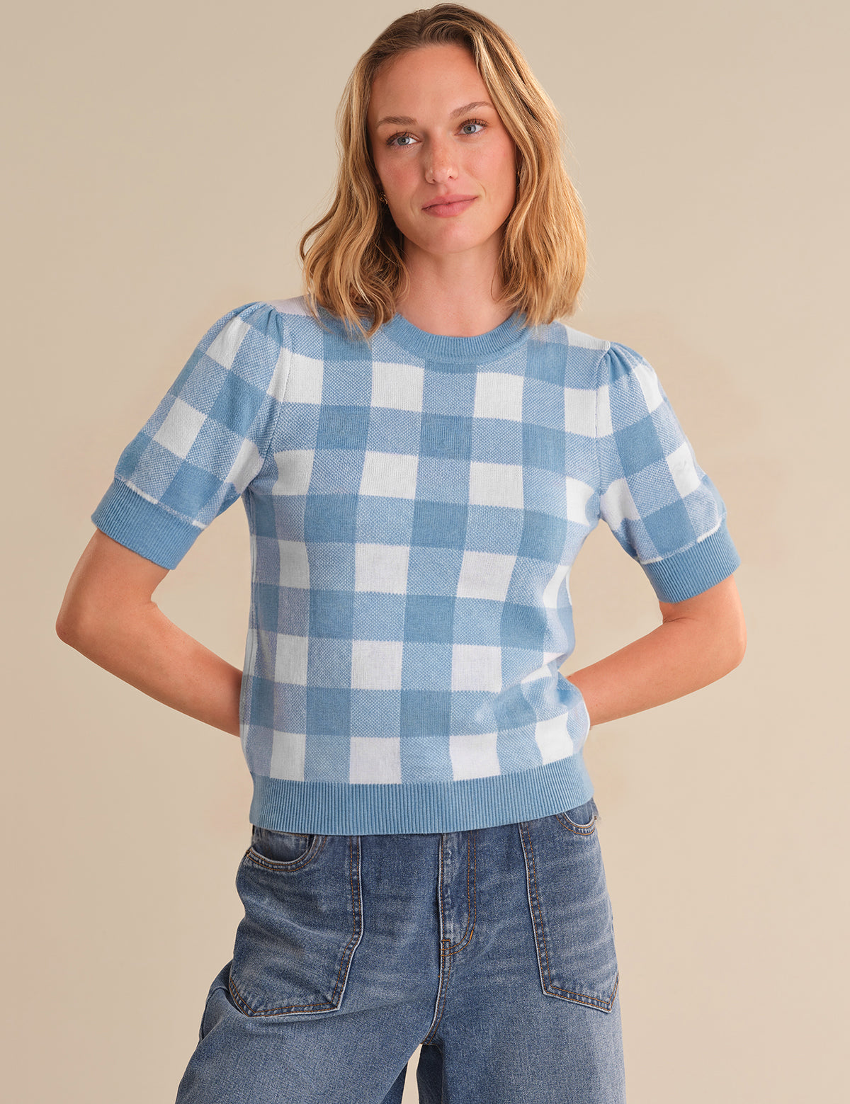 Woman wearing a blue and white checkered sweater against a beige background