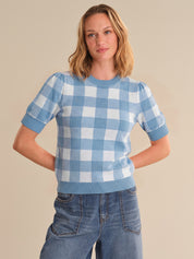 Woman wearing a blue and white checkered sweater against a beige background