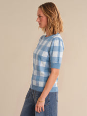 Woman wearing a blue and white checkered shirt against a beige background