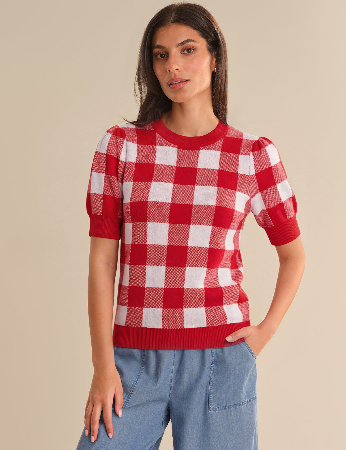 Woman wearing a red and white checkered shirt against a beige background