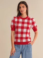 Woman wearing a red and white checkered shirt against a beige background