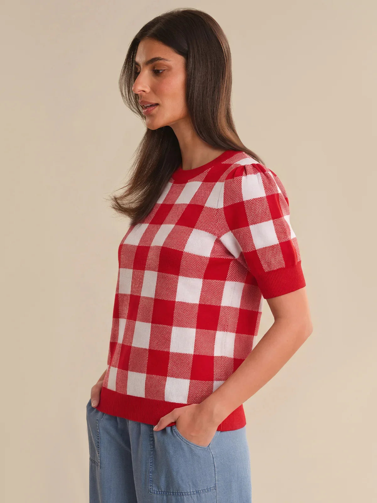 Woman wearing a red and white checkered shirt against a beige background