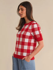 Woman wearing a red and white checkered shirt against a beige background
