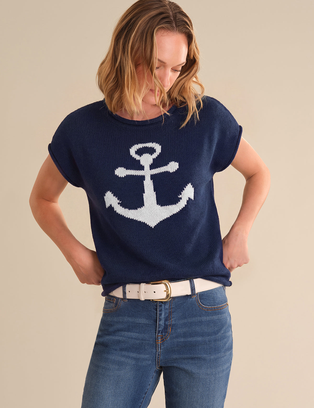 Woman wearing a navy blue sweater with a white anchor design on a beige background