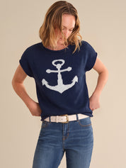 Woman wearing a navy blue sweater with a white anchor design on a beige background