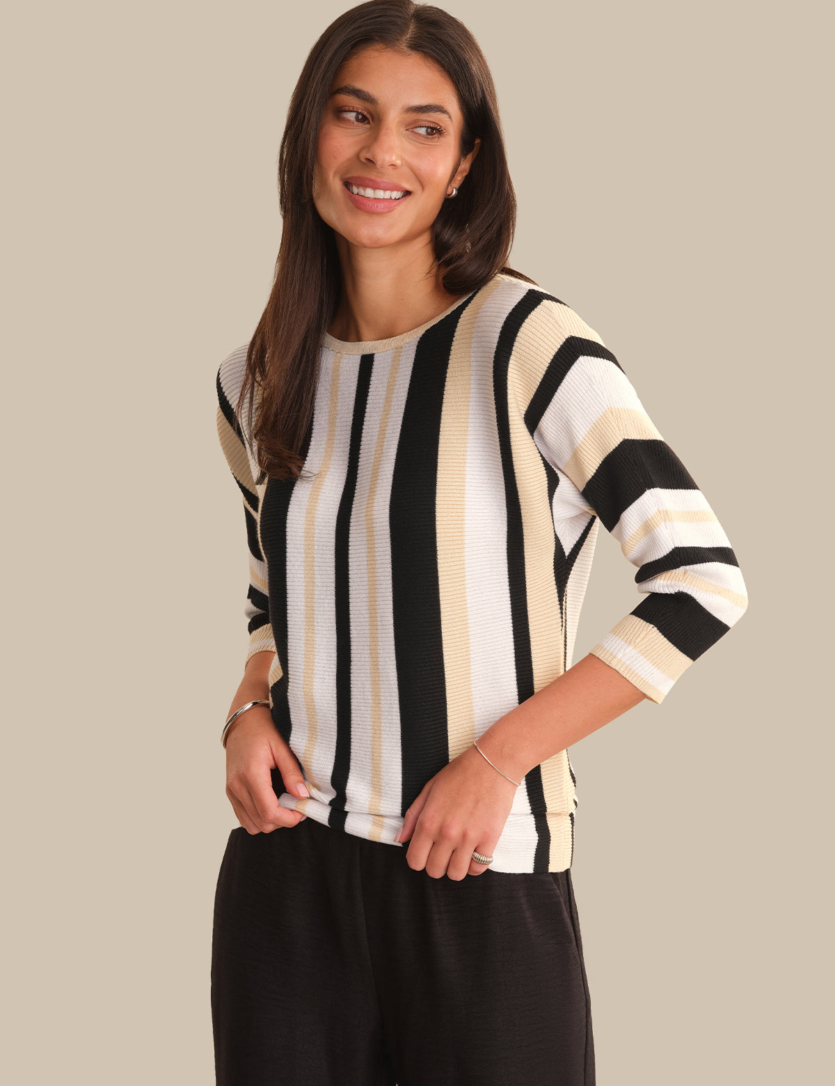 Woman wearing a black and white striped sweater against a beige background