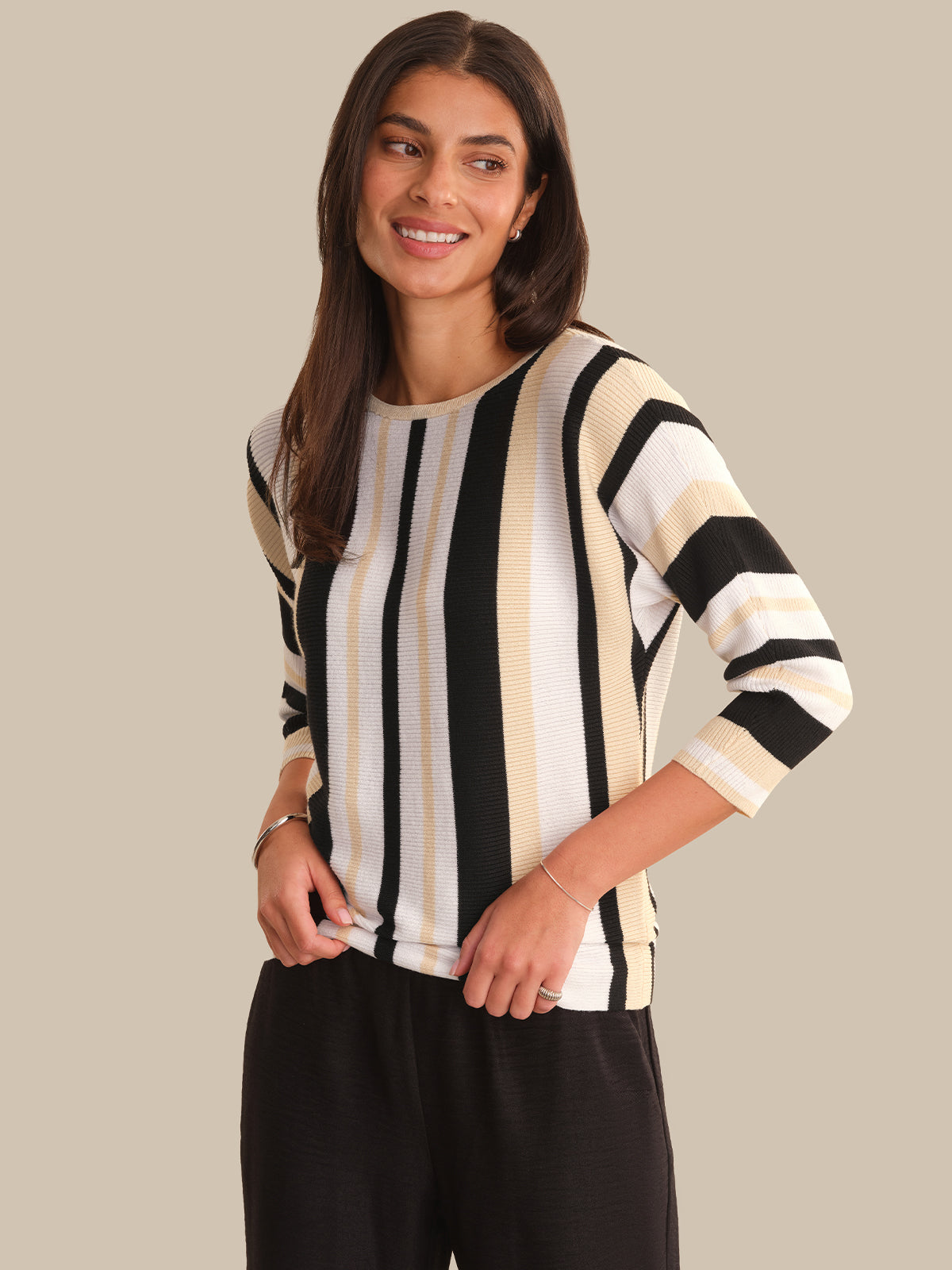 Woman wearing a black and white striped sweater against a beige background