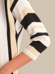 Close-up of a striped sweater sleeve with black, beige, and white colors on a neutral background.