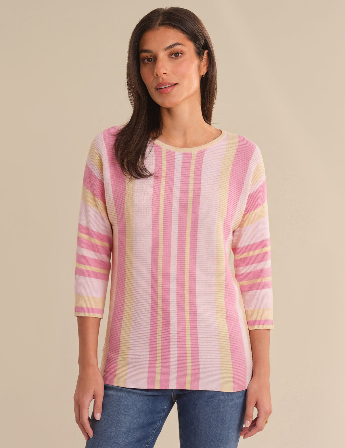 Woman wearing a pink and yellow striped sweater against a beige background