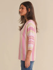 Woman wearing a pink and beige striped sweater against a beige background