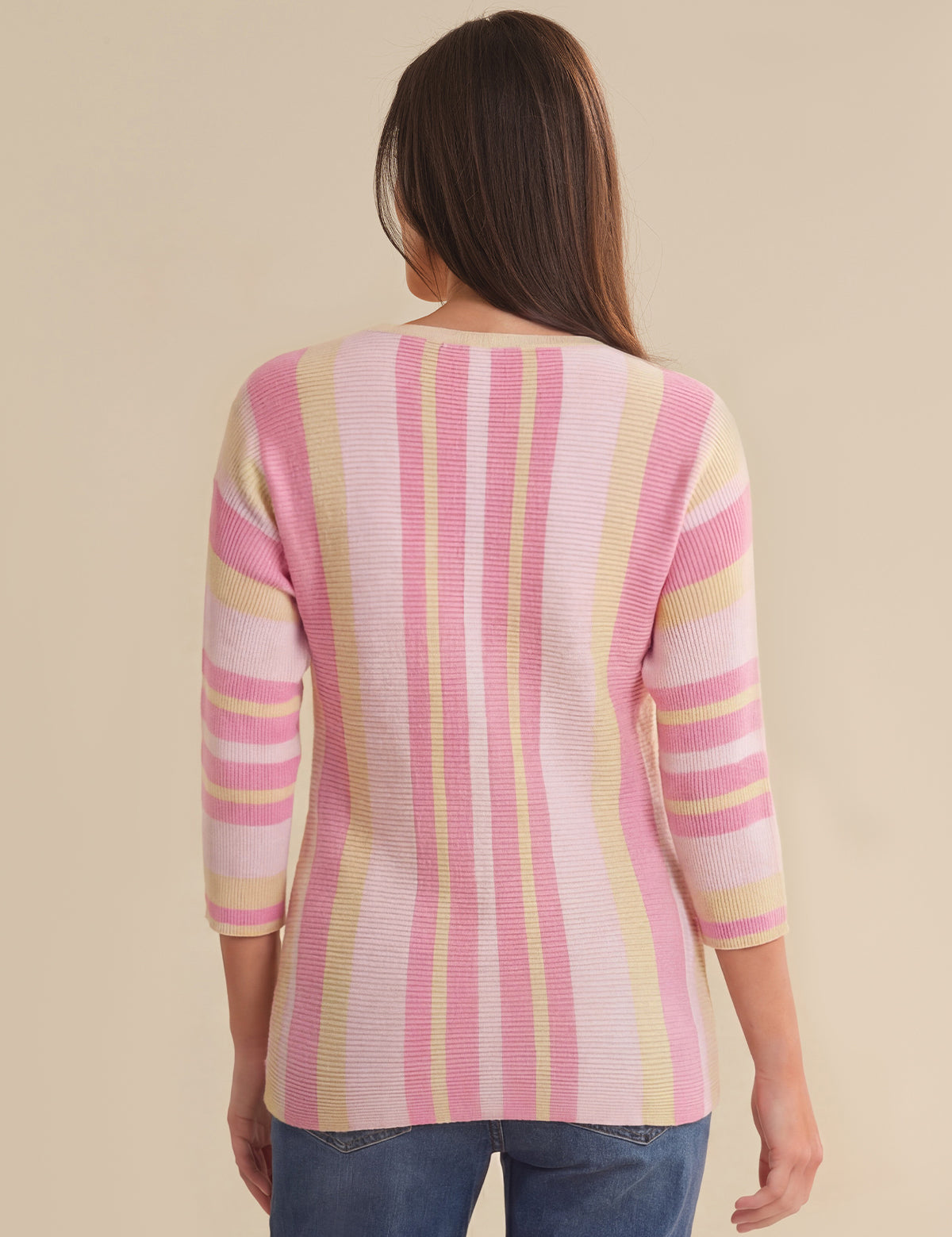 Woman wearing a pink and yellow striped sweater against a beige background