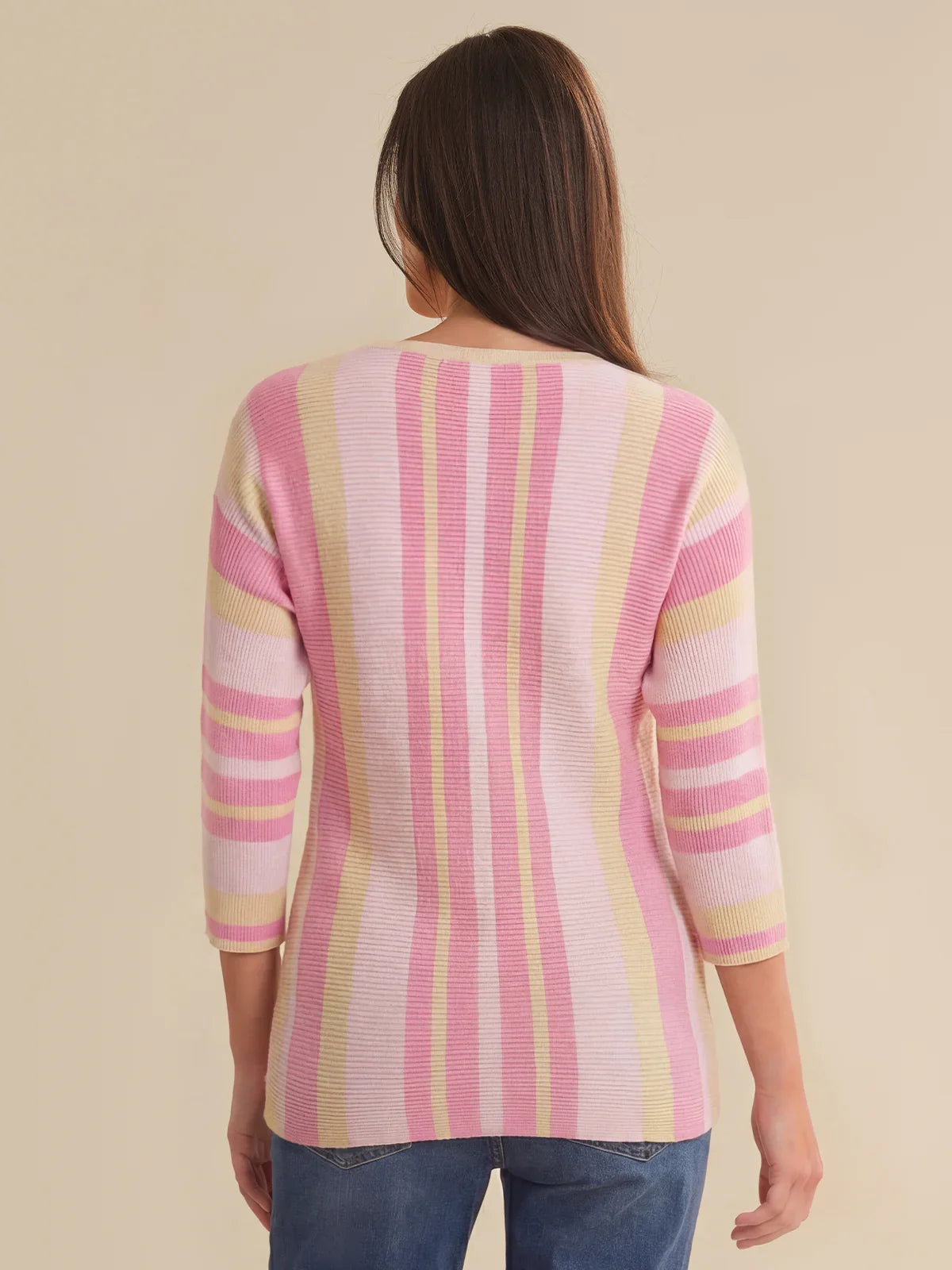 Woman wearing a pink and yellow striped sweater against a beige background
