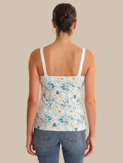 Woman wearing a floral tank top and jeans on a beige background