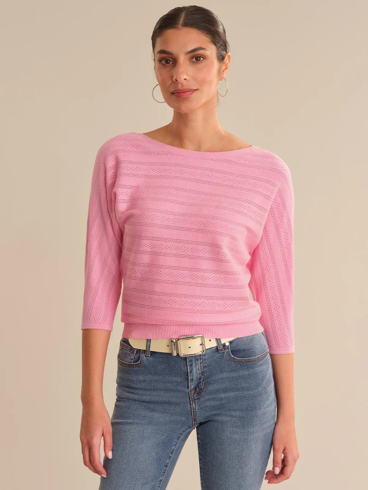 Woman wearing a pink sweater and blue jeans on a beige background