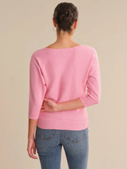 Person wearing a pink sweater and blue jeans on a beige background