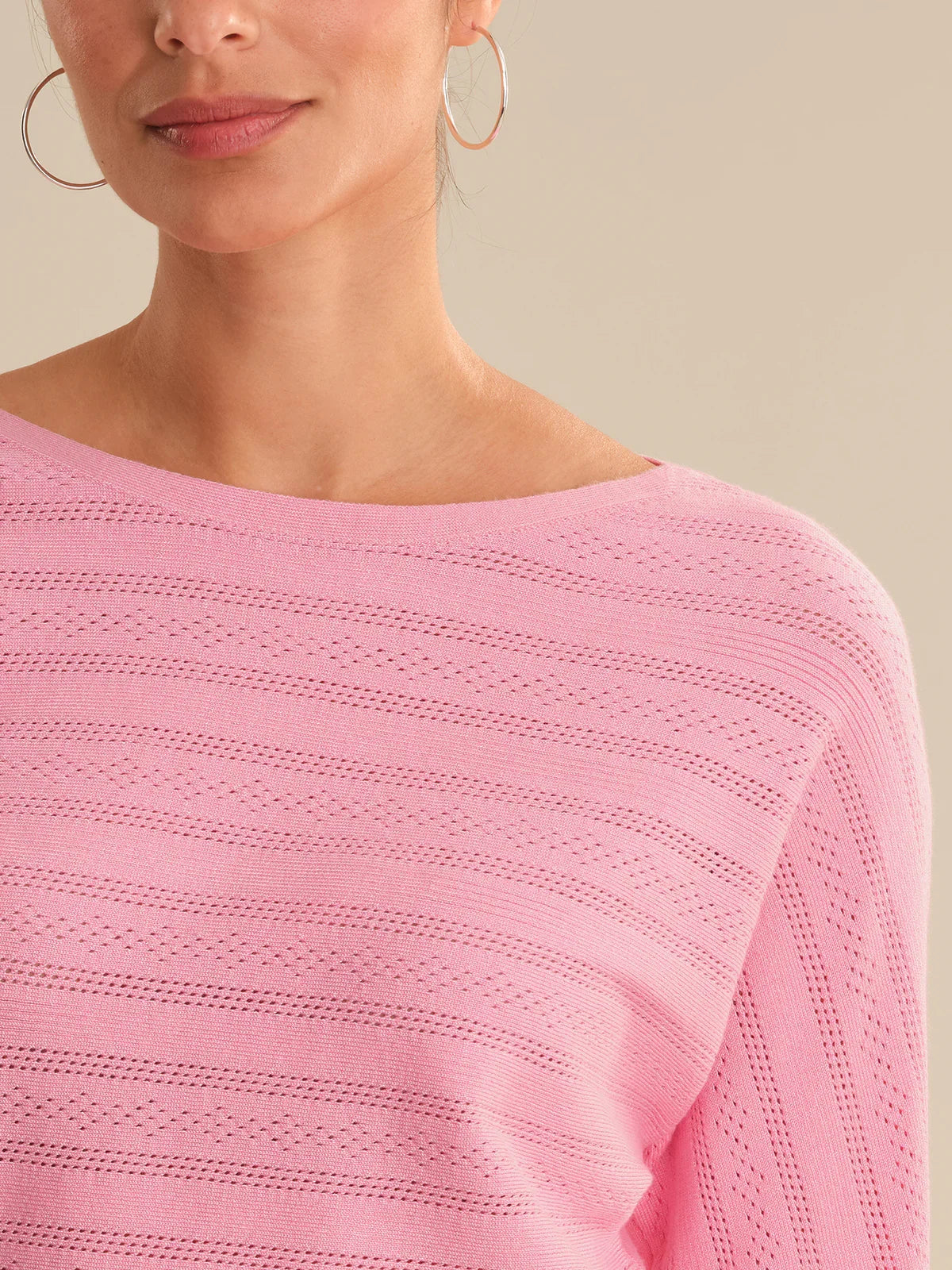 Close-up of a person wearing a pink sweater with a neutral background